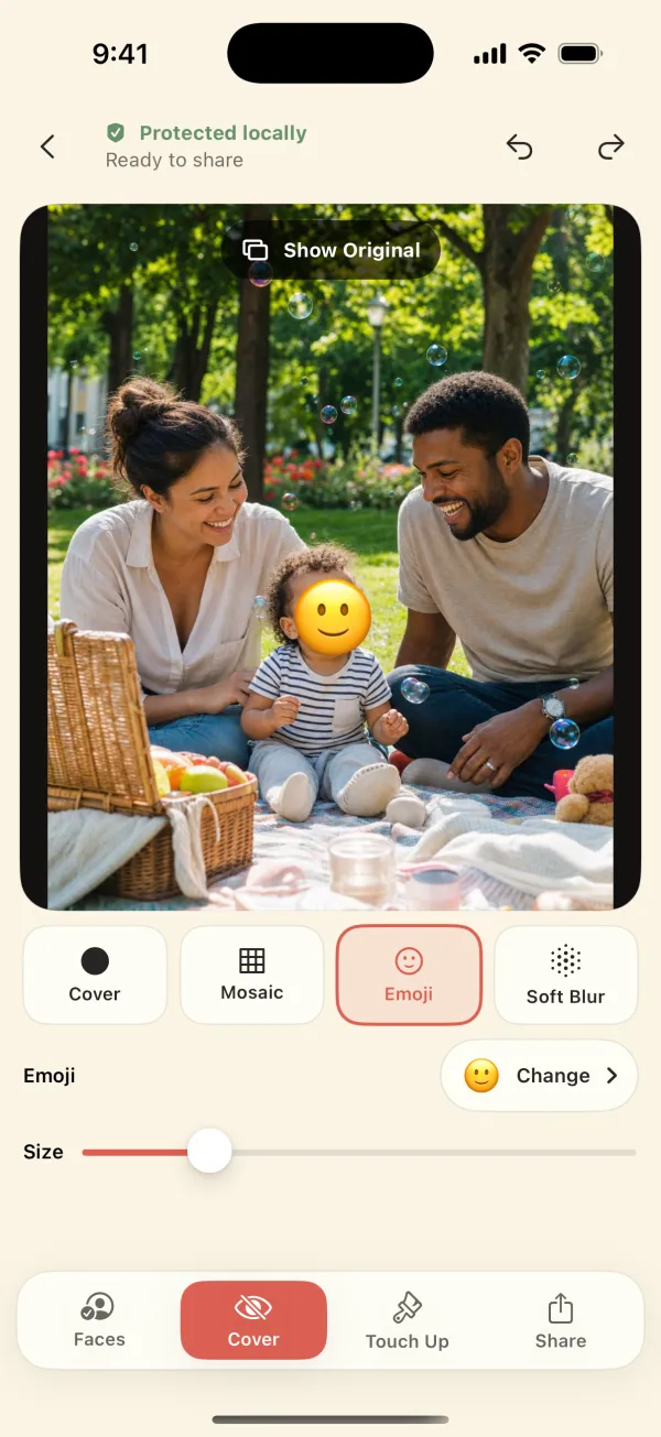 Emoji style: a baby's face covered by a smiling emoji at a family picnic